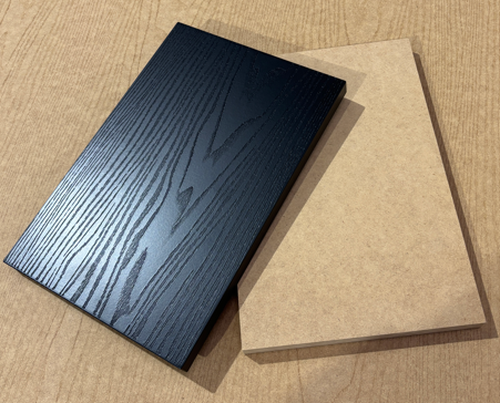 Embossed timber-grain panel finished in black beside a raw MDF board